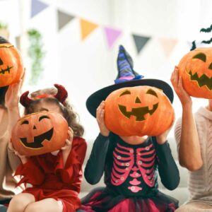 Børn klædt i Halloween-kostumer med græskarhoveder – farverigt og kreativt Halloween tøj til børn, perfekt til udklædningsfester og trick-or-treat.