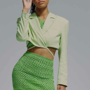 Kvinde iført moderne grønt tøj med hæklet nederdel og cropped blazer – trendy og stilfuldt look i friske grønne nuancer.